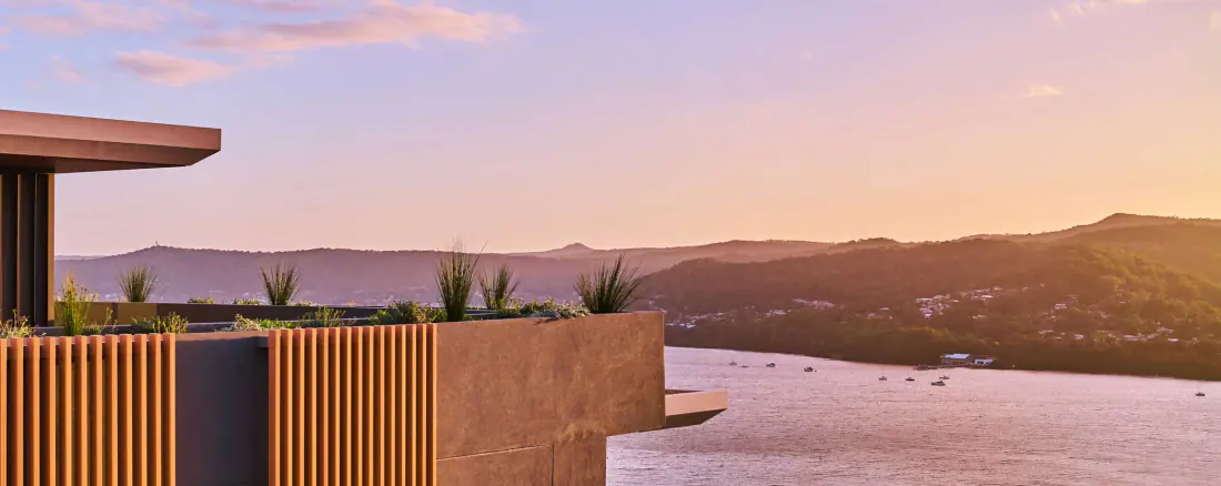 Timber-screened terrace at Rumbalara Residences looking out over the water at sunset