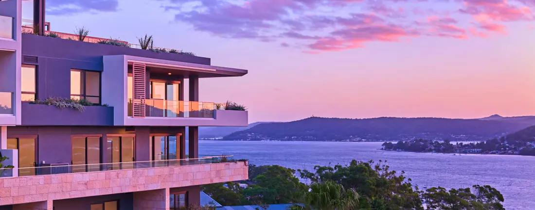 Balconies at Rumbalara Residences against a pink dusk sky over Brisbane Water